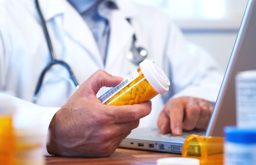 Pharmacist with bottles and laptop